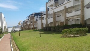 A row of modern apartment buildings with a paved walkway and a grassy area in between. - Al Cudia Smir Beach Resort (Fnideq)