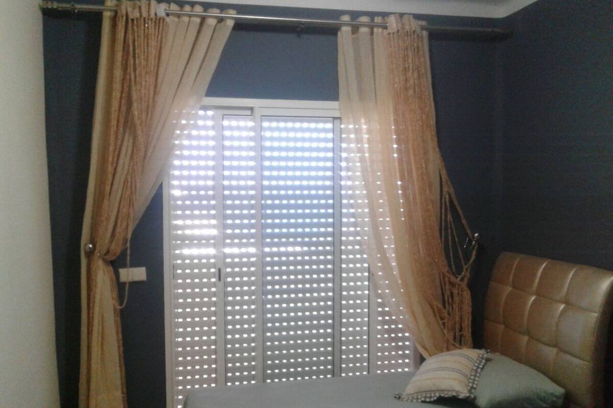 A bedroom with a bed, curtains, and a window with blinds.