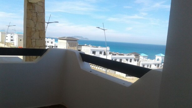 A balcony with a view of the sea and buildings. - Al Cudia Smir Beach Resort (Fnideq)