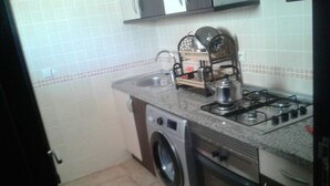 A compact kitchen with a washing machine, a gas stove, and a sink. - Al Cudia Smir Beach Resort (Fnideq)