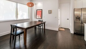 Eine moderne Küche mit dunklem Holzboden, einem Edelstahlkühlschrank und einem Essbereich mit Holztisch und Stühlen.