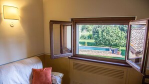 Une pièce avec une fenêtre donnant sur un jardin, un radiateur et un luminaire fixé au mur.