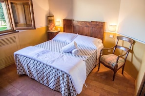 Cozy retreat with a neatly made bed, wooden headboard, and comfortable chair.