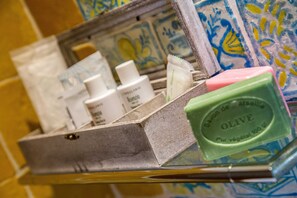A toiletry station with a metal shelf and a selection of personal care items, including a bar of olive soap.