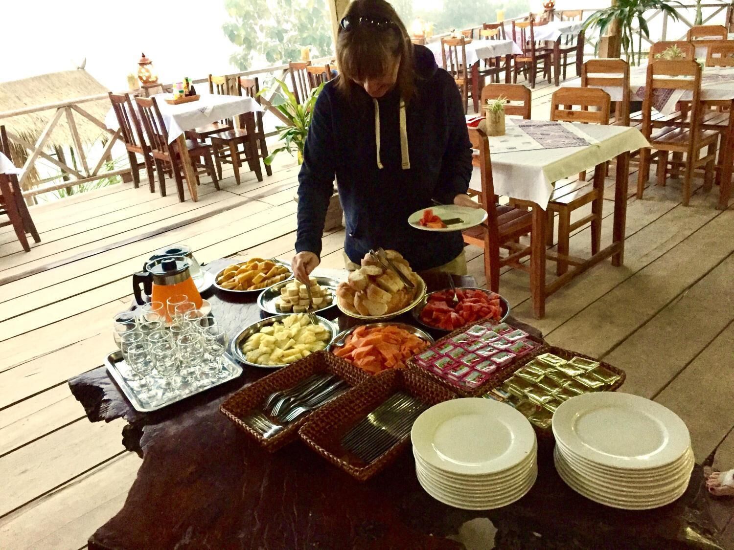 Una mesa de madera con una variedad de alimentos y utensilios para un servicio tipo bufé.