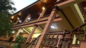 Um edifício com vários andares, varanda, grades de madeira e escadaria.