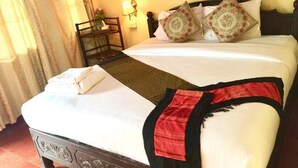 Uma cama bem arrumada com manta vermelha e preta, dois travesseiros e uma mesa de cabeceira com abajur.