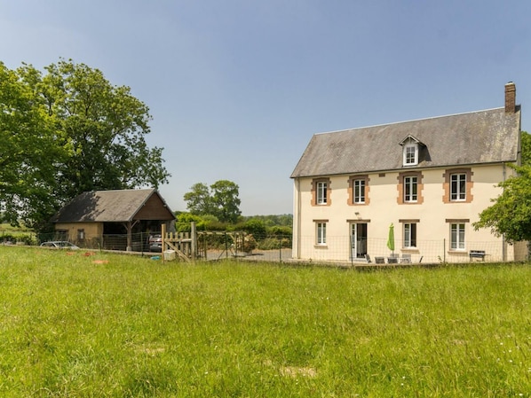 A large two-story house with a sloped roof and a small attached barn.