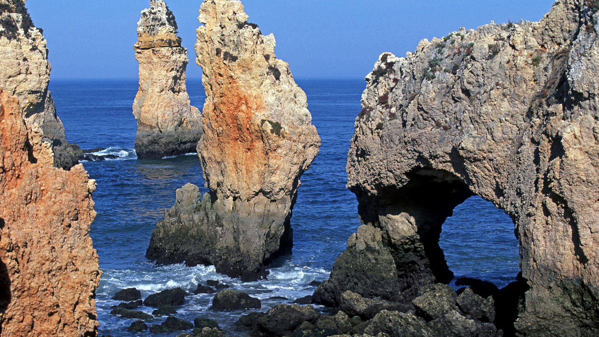 A coastal landscape with prominent rock formations and a clear blue sea.