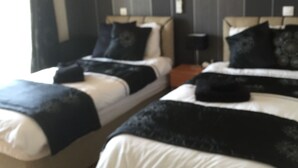 Quarto de hotel com duas camas, um quadro na parede e uma janela com cortinas.