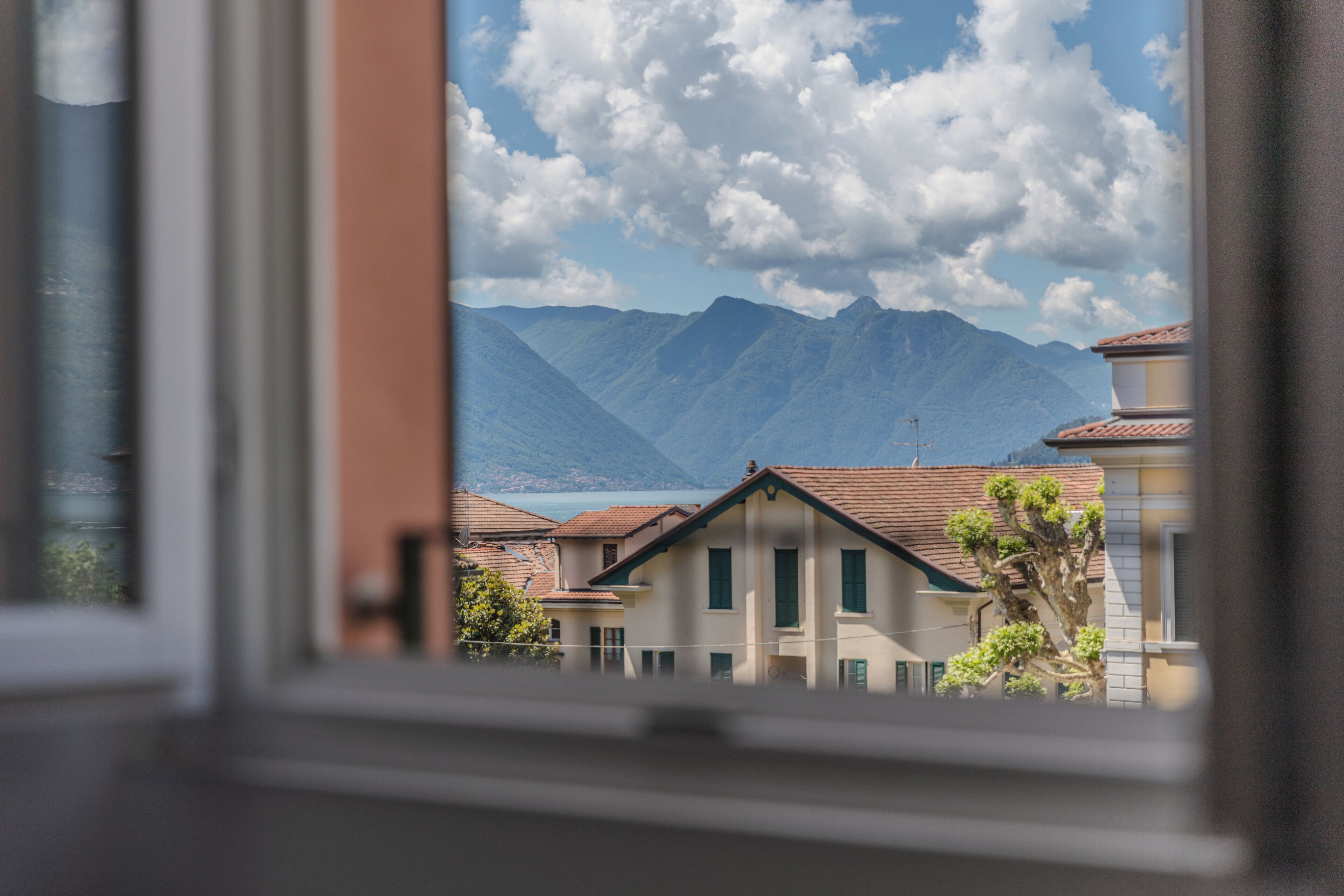A view through a window of a building with a mountain and a lake in the background.