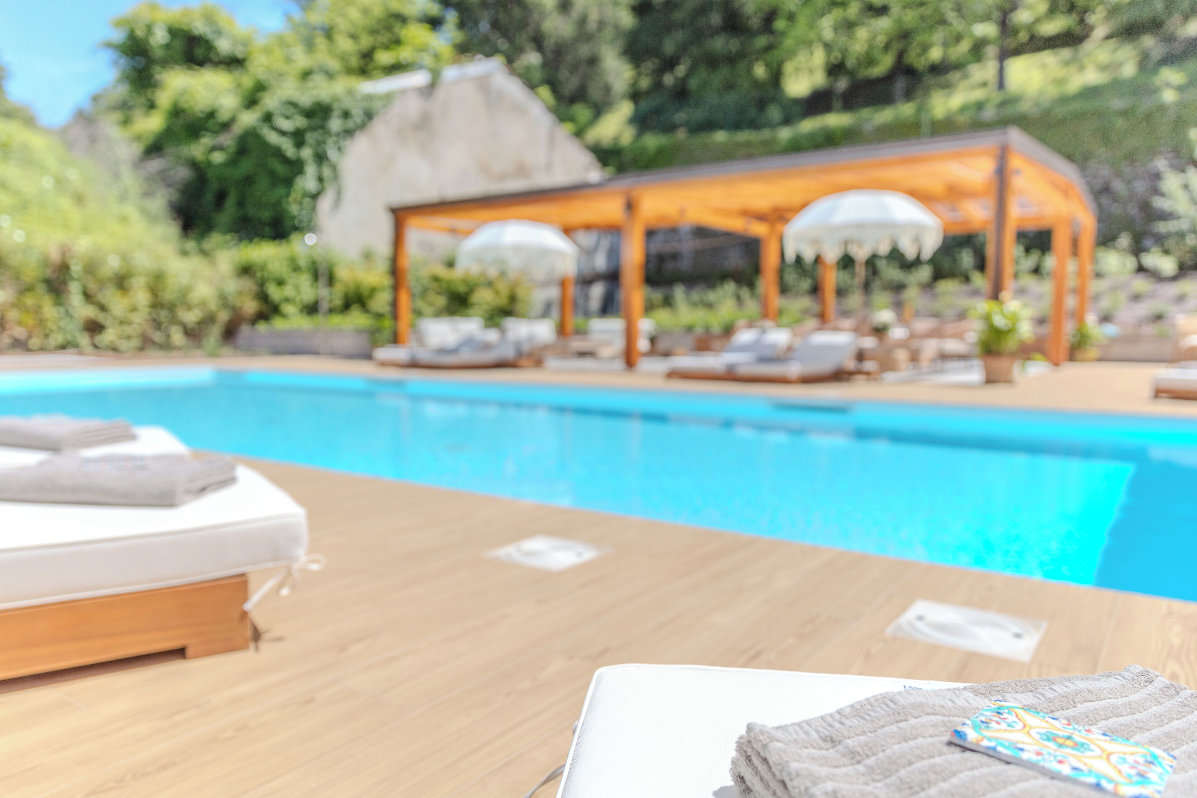 A poolside area with a wooden table, a white towel, and a lounge chair.