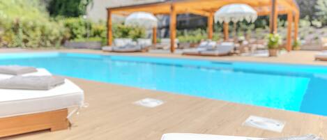 A poolside area with a wooden table, a white towel, and a lounge chair.