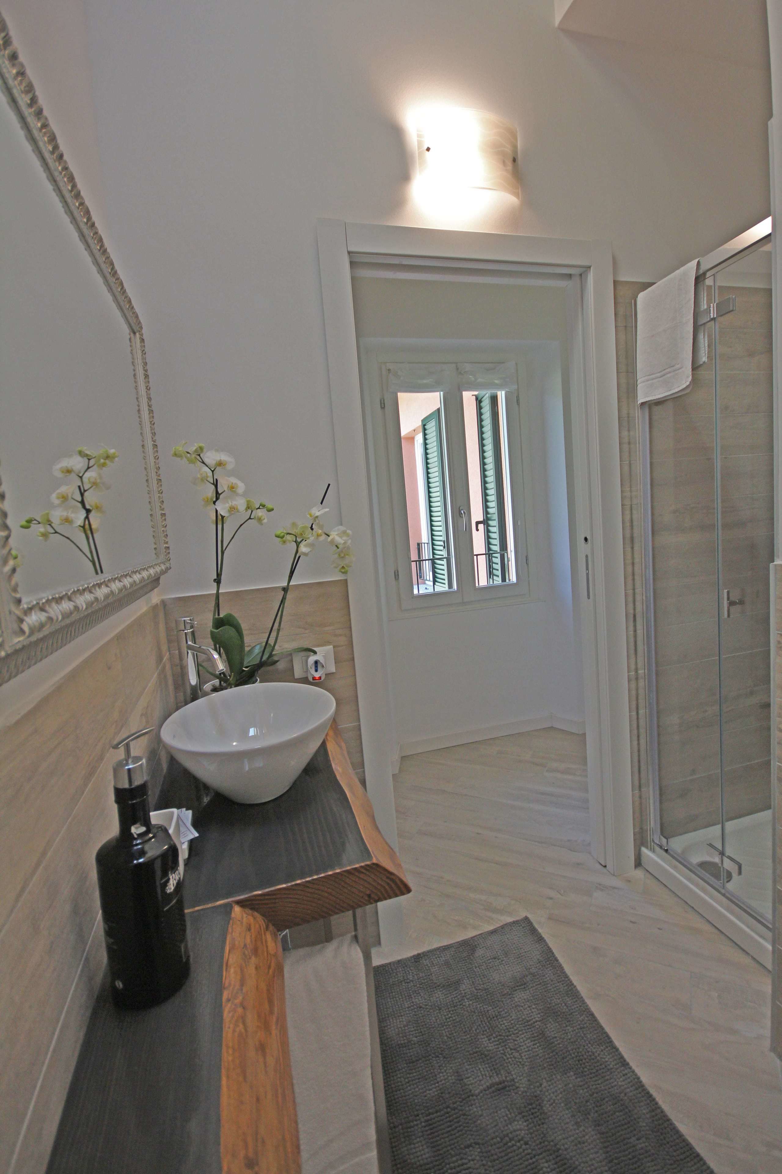A bathroom with a white sink, a mirror, and a shower area.