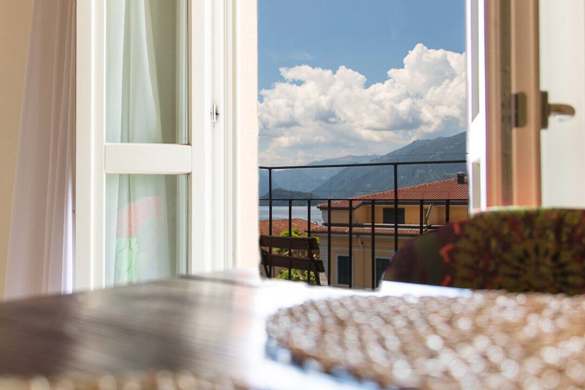 Una habitación con vistas a montañas y un lago, visible a través de una puerta abierta.