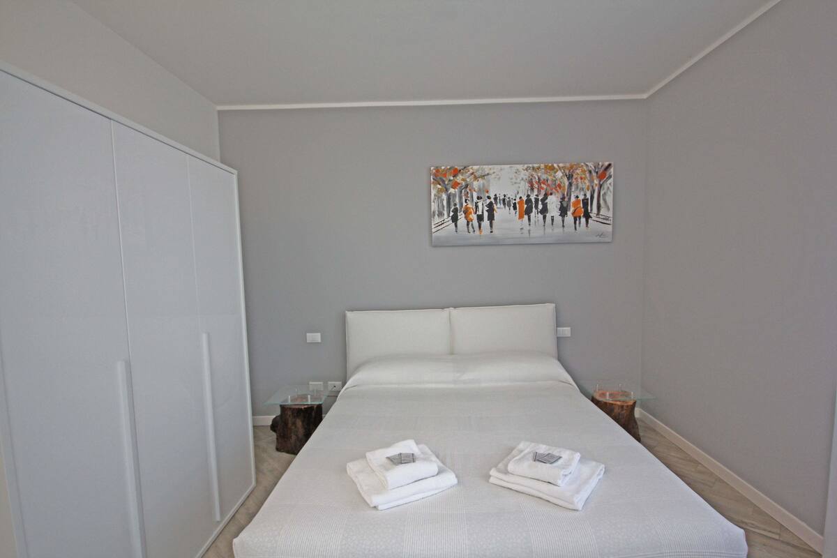 Una habitación de hotel con una cama grande, un cuadro en la pared y un armario.
