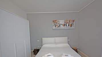 Una habitación de hotel con una cama grande, un cuadro en la pared y un armario.