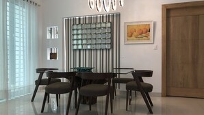 A modern dining area with a glass-top table, dark chairs, a decorative wall panel, and a framed artwork. - III Verdana Rental (Puñal)