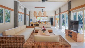 A spacious living area with a sofa, coffee table, and TV stand. - Villa La Luvier (Canggu)