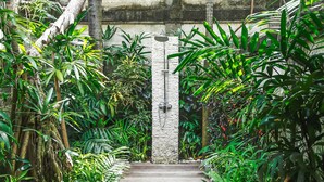 A stone pathway leading to a door framed by lush tropical plants. - Villa La Luvier (Canggu)