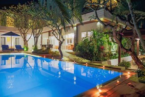 Una piscina al aire libre, sillones reclinables de piscina