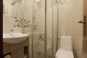 A bathroom with a glass-enclosed shower, a sink, and a toilet.
