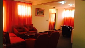 A hotel room with red curtains, a painting on the wall, and a desk with a chair. - Guesthouse Tara (Belgrade)