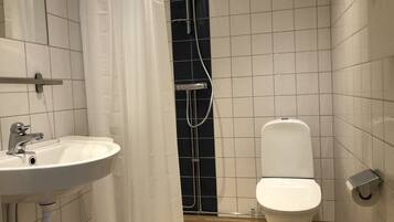 A bathroom with a white sink, a toilet, and a shower area.