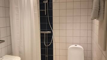 Un baño pequeño y moderno con ducha, inodoro y lavamanos.