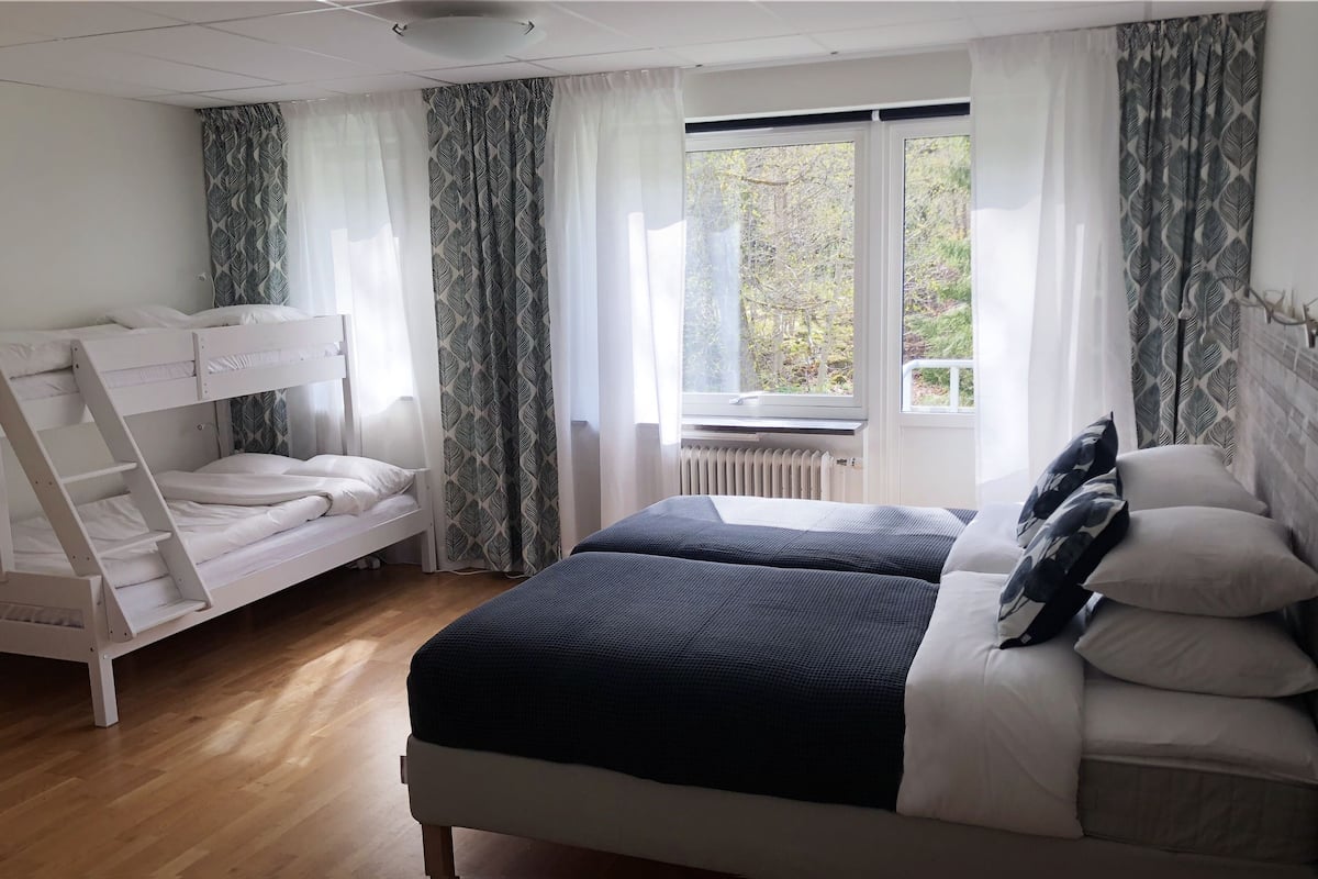 A bedroom with a bunk bed, a double bed, and a radiator.