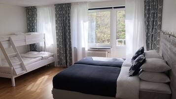 Ett sovrum med en våningssäng, en dubbelsäng och ett element.