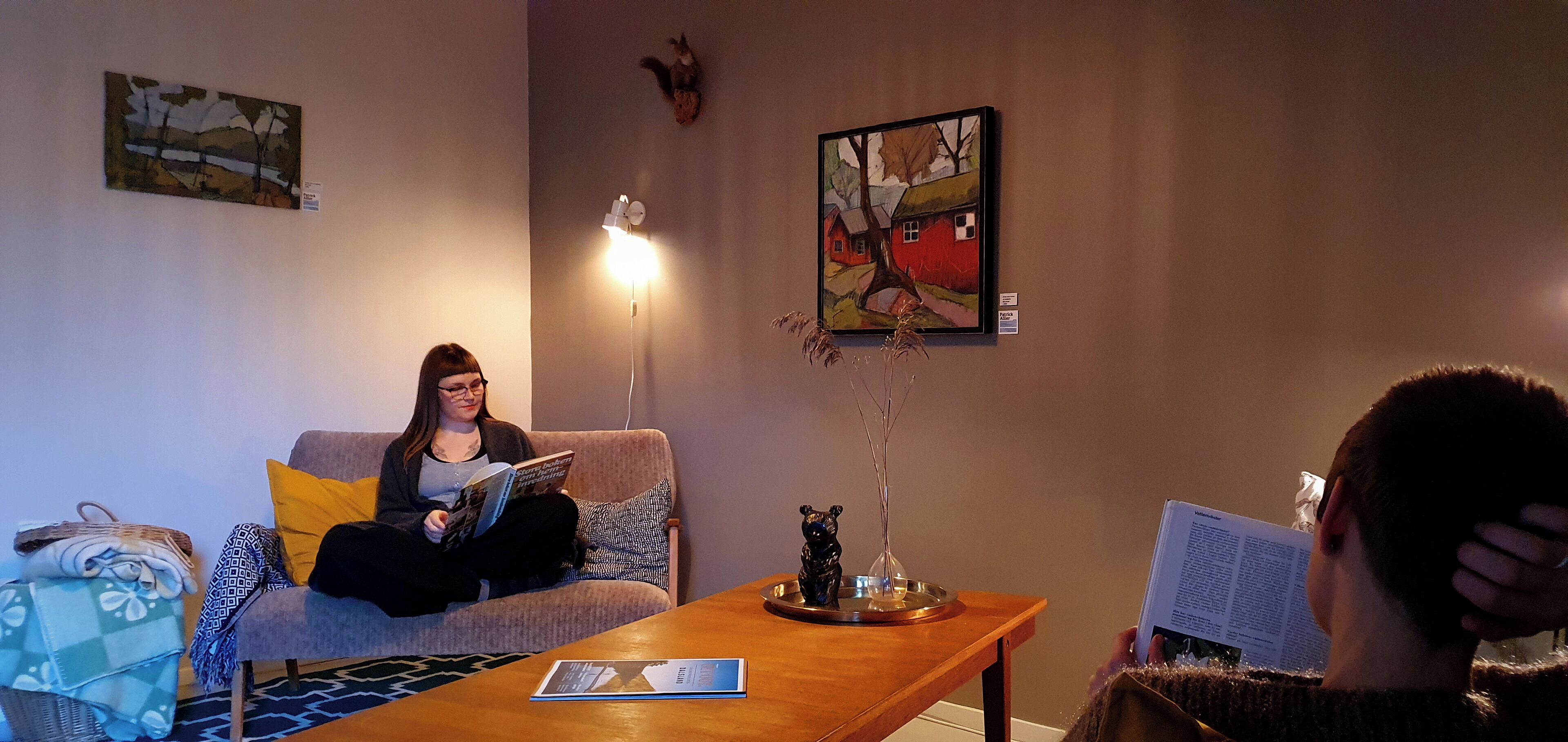 A room with a sofa, a coffee table, and a painting on the wall.