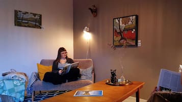 A room with a sofa, a coffee table, and a painting on the wall.