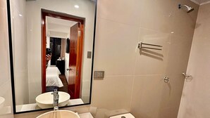 A modern bathroom with a large mirror, a sink, a toilet, and a shower. - Mama's House (Cusco)
