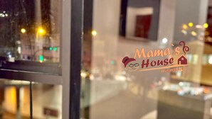 A wooden stool with a tray of white teapots and cups, a sugar container, and a creamer, set against a window with a city view. - Mama's House (Cusco)