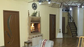 A living room with a fireplace, a staircase, and a clock on the wall.