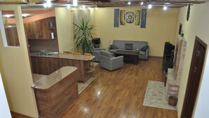 A compact living space with a kitchen area, a dining table, a sofa, and a large plant.