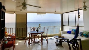 Een balkon met een tafel, stoelen, een bank en uitzicht op zee.