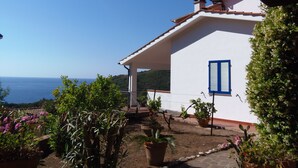 Un bâtiment blanc avec des volets bleus, une véranda et une vue sur la mer.