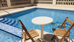 A pool area with two wooden chairs and a small round table. - SUPER VIEWS IN SUIT. NEW WITH FREE WIFI / PETS PERMITTED!(4 people) (Benidorm)