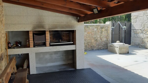 An outdoor kitchen with a brick oven, a sink, and a stone wall.