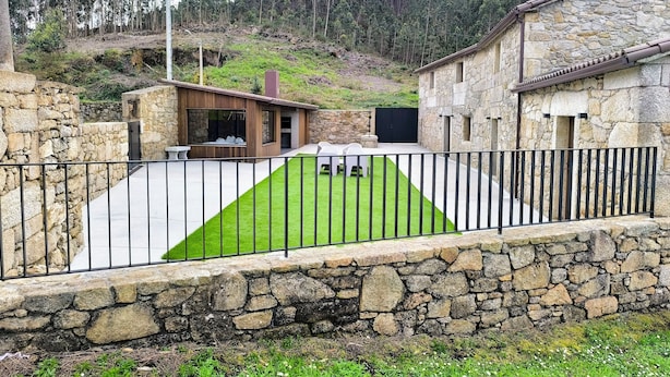 A stone building with a stone wall and a grassy lawn.