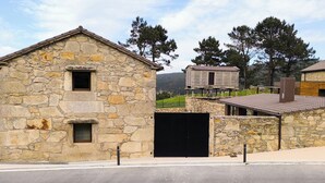 Un edificio de piedra con una puerta negra, un ventanal pequeño y una chimenea.