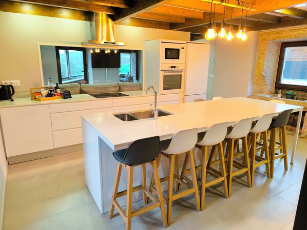 A modern kitchen with a central island, bar stools, a built-in oven, and a large window.