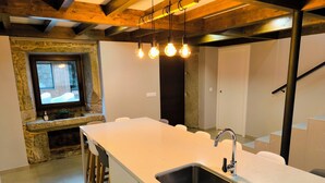 Una cocina moderna con una isla grande, pileta de acero inoxidable y taburetes de madera.