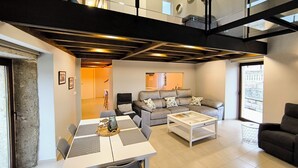 Un espacio habitable moderno con comedor, sofá y mesa de centro. Se ve una escalera que sube a un nivel superior.