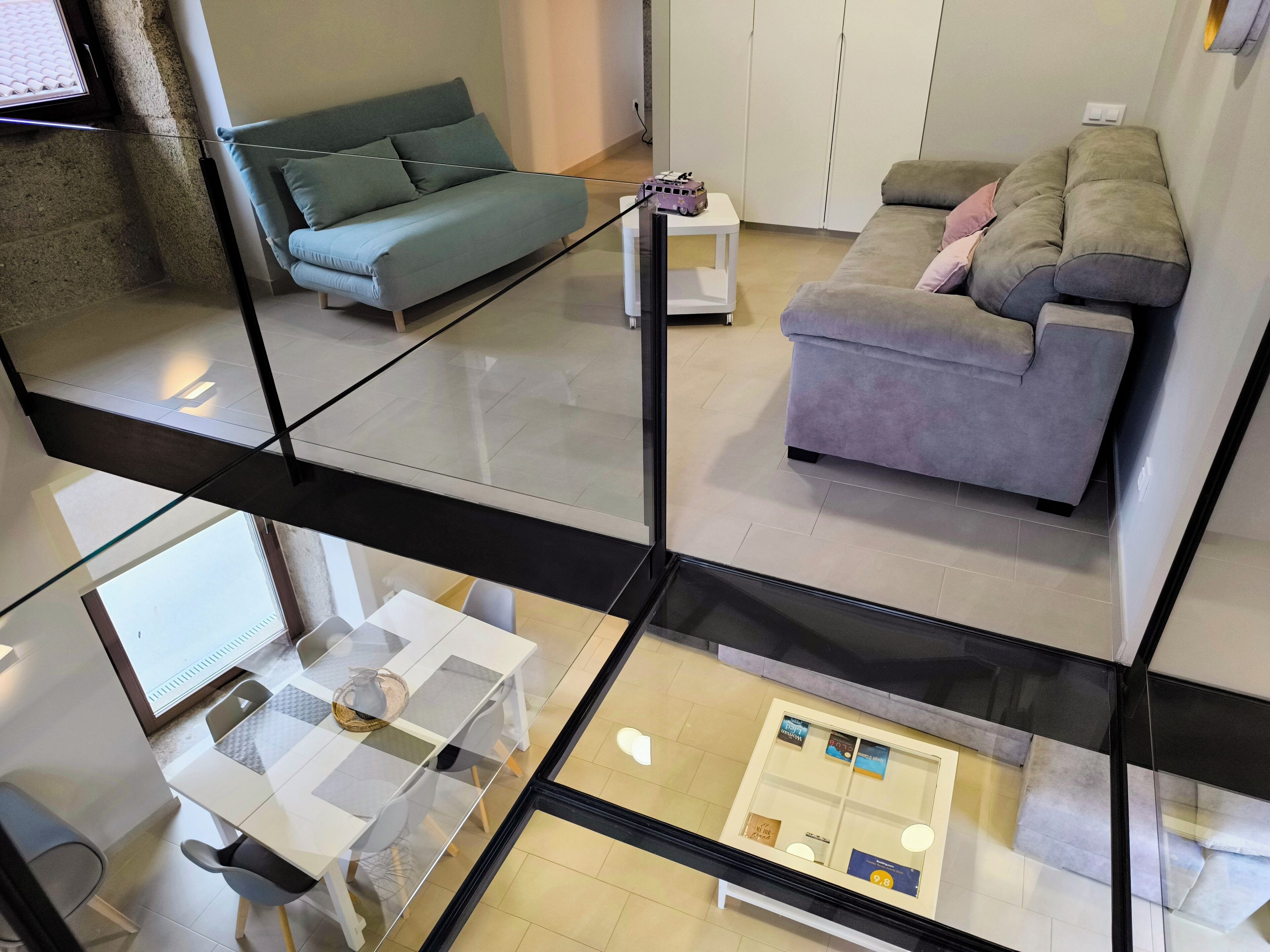 Eine moderne Wohnung mit einem Glasbalkon, einem Essbereich mit Tisch und Stühlen sowie zwei Sofas im Wohnzimmer.