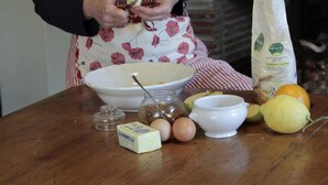 En person står vid en köksbänk med olika livsmedel och ingredienser framför sig.