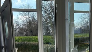 A room with a large glass door leading to a garden. - Haffnest with wonderful views of the Salzhaff  (Rerik)