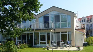A two-story residential building with a balcony, large windows, and a well-maintained lawn. - Haffnest with wonderful views of the Salzhaff  (Rerik)